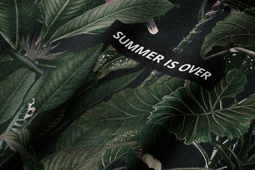 PSD mockup of a hoodie showing realistic leaf patterns and a sewn-on black tag with bold lettering.