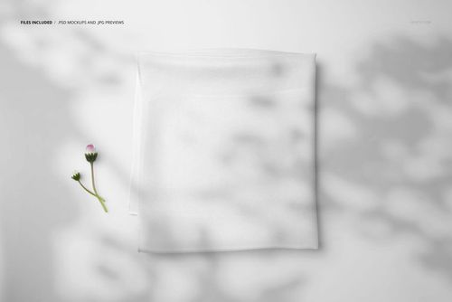 White silk scarf mockup shown folded neatly, viewed from above, next to a delicate flower and shadow patterns.