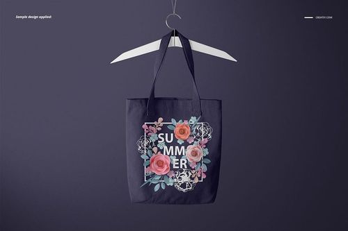 Front view of a polyester tote bag mockup hanging on a white clothes hanger, featuring a floral summer design.
