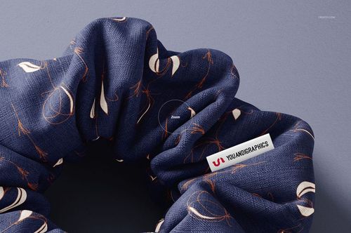 Detailed top view of a fabric hair scrunchie mockup featuring navy blue color and scattered abstract designs.