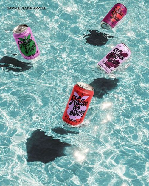 Floating drink cans with vibrant designs and hard shadows on rippling water, viewed from above in a PSD mockup.