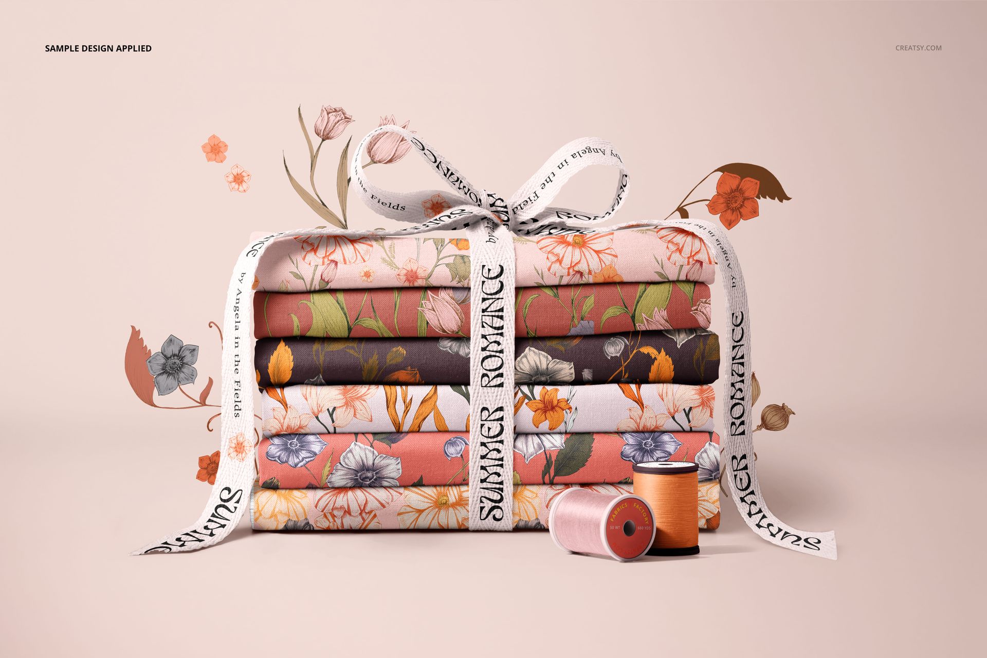 PSD mockup showing a bundle of patterned fabrics in various colors, tied with a ribbon and accompanied by spools of thread.
