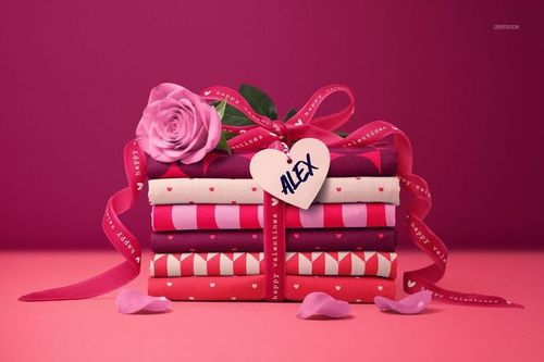 Valentine's Day themed mockup featuring stacked fabric bundles in shades of red and pink, ribbon, and rose petals.