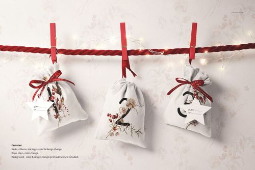 PSD mockup showing three decorative drawstring sacks with holiday prints, hanging on a rope with red clothespins.