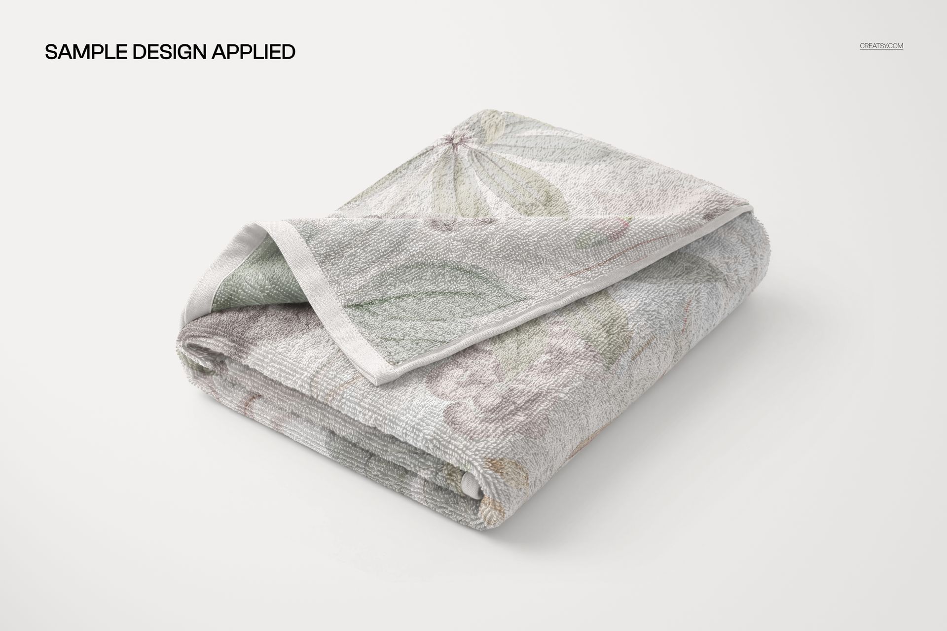 Towel mockup featuring a folded textile with a soft leaf and flower design, shown from a slightly angled perspective.