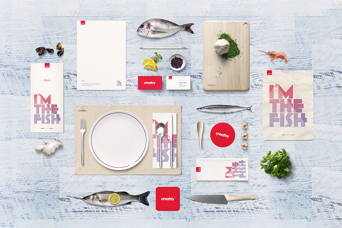Seafood restaurant table setting mockup with plates, cutlery, fish, menu cards, and fresh ingredients on a light wood surface.