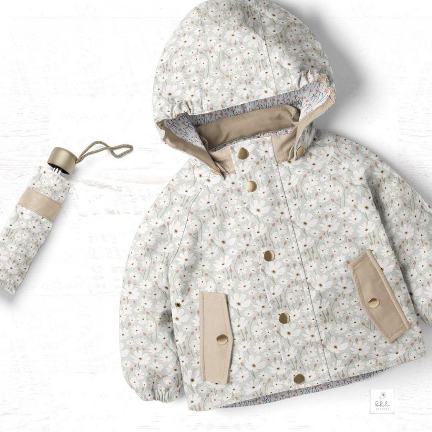 Kids rainwear mockup featuring a light-colored floral patterned jacket with a hood and matching umbrella on a white wooden surface.