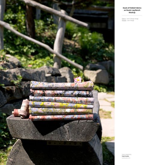 PSD mockup showing multiple folded fabrics with colorful designs outdoors, with natural stone and wood elements nearby.