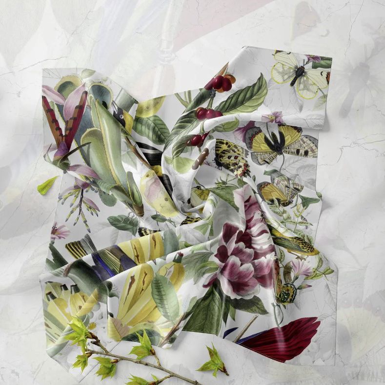 Crumpled square silk scarf mockup featuring a botanical and insect print with butterflies, leaves, and flowers on a light surface.