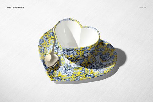 Heart-shaped cup mockup set with saucer and spoon, decorated in blue and yellow paisley, viewed from above.