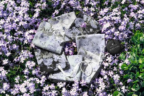 PSD mockup showing assorted fabric swatches with botanical designs placed on vibrant garden flowers.