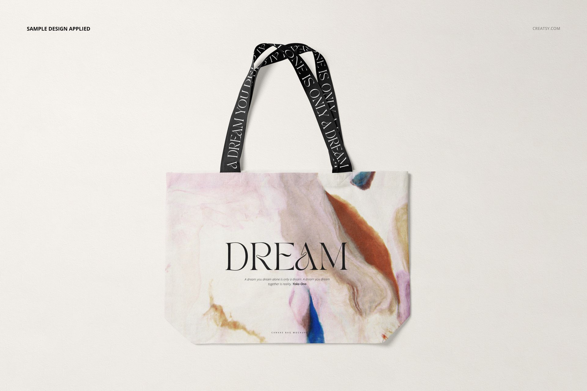 Front view of a shopper canvas bag mockup with abstract pastel patterns and black handles featuring white text.
