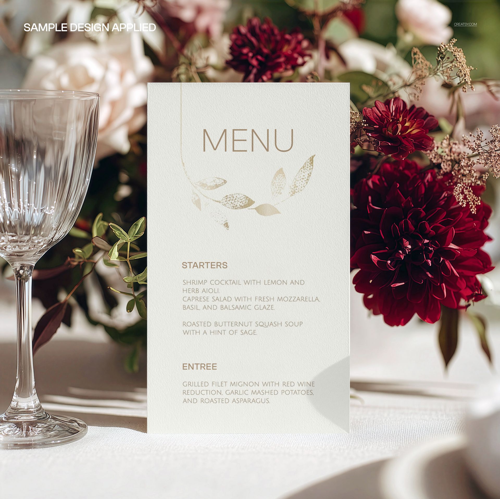 Elegant floral menu card mockup on a wedding table, featuring gold leaves and placed near wine glasses and flowers.