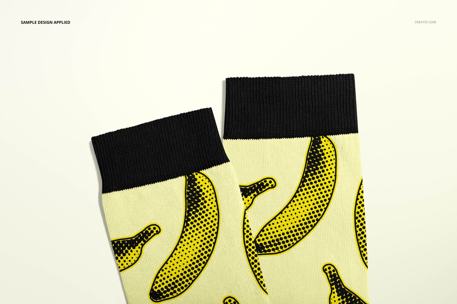 Medium cuff socks mockup featuring a repeating yellow banana print and solid black cuffs, shown from above.