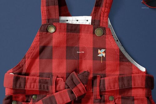 Front view of a baby dress mockup with red and black plaid pattern, corduroy texture, and decorative buttons.