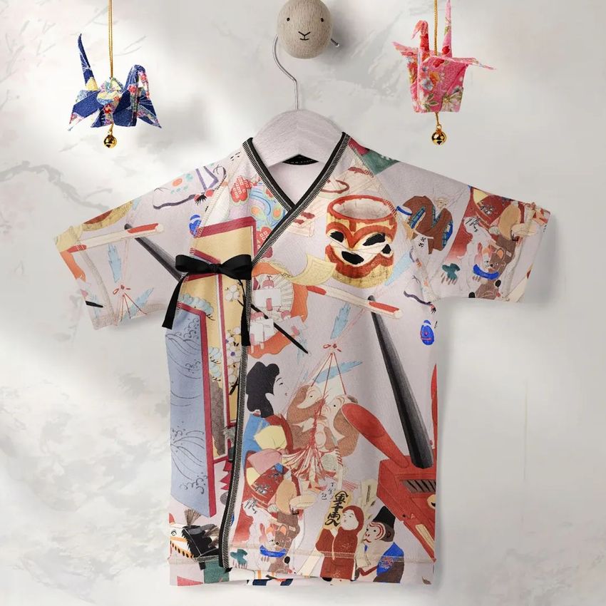 Baby kimono bodysuit mockup with colorful illustrated pattern, hanging on a wall with origami cranes and a plush animal hook.