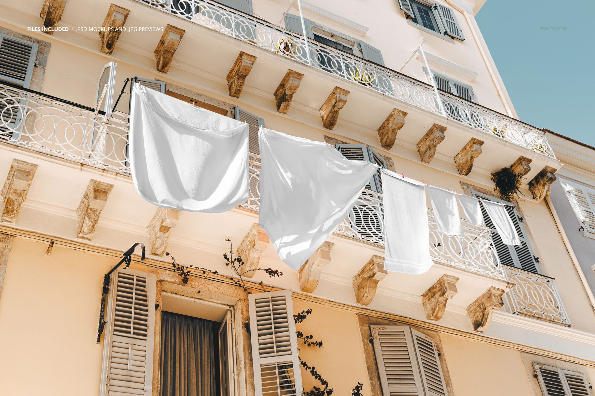 PSD mockup showing various white fabrics suspended from a balcony on a pale building, viewed from below in bright outdoor light.