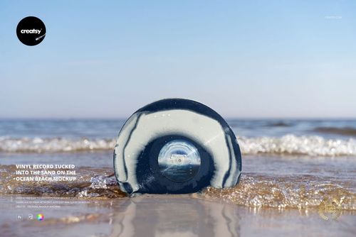 Blue and white vinyl record mockup resting in wet sand at the edge of the beach with waves in the background.