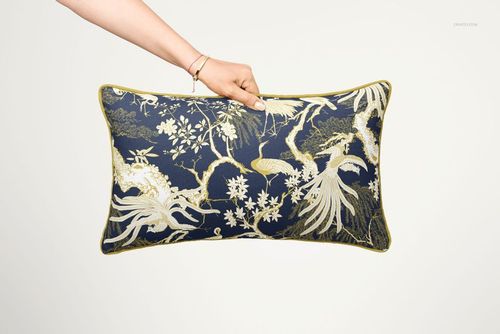 Decorative pillow mockup with piped trim, showing a detailed floral and bird design in blue and gold tones.