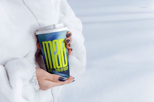 Close-up of hands with dark nail polish holding a paper cup mockup with a white lid and colorful graphic pattern.