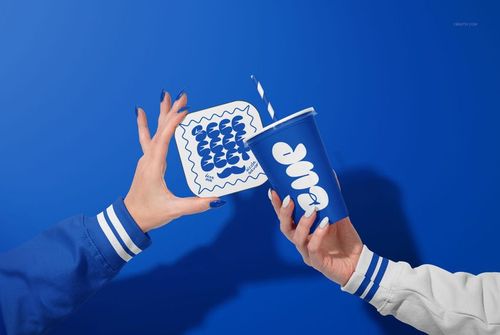 Close-up of blue and white vegan burger bar packaging mockup, featuring a cup and food box with graphic designs.