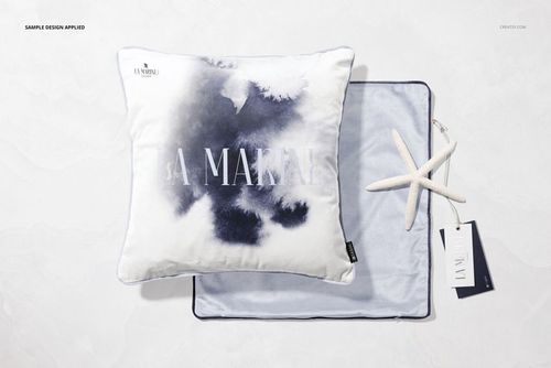 PSD mockup set displaying a square pillow with abstract blue pattern, round cushion underneath, starfish, and tag on a marble tabletop.
