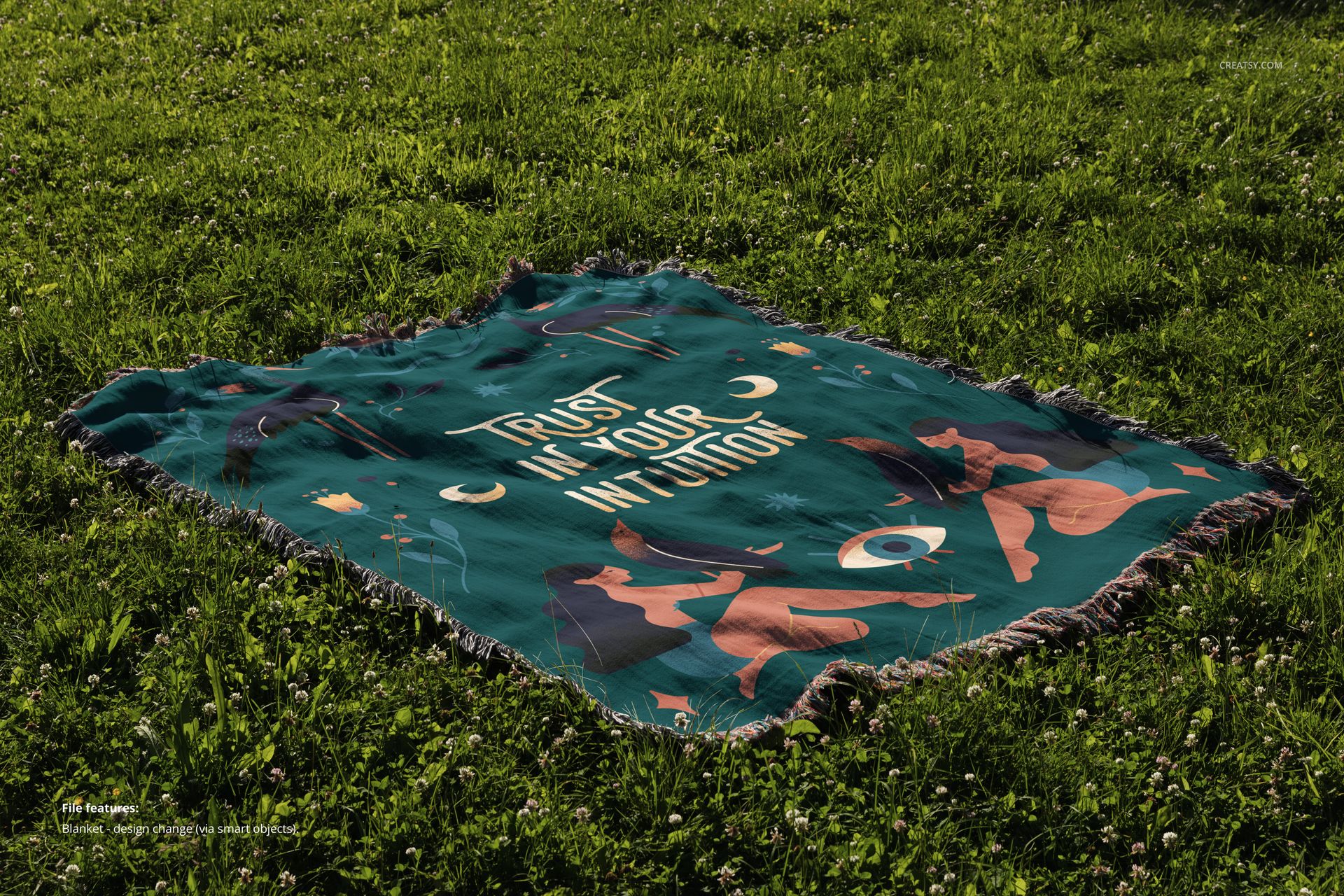 Mockup of a woven throw blanket with fringed edges, featuring colorful art and text, displayed on a grassy lawn.