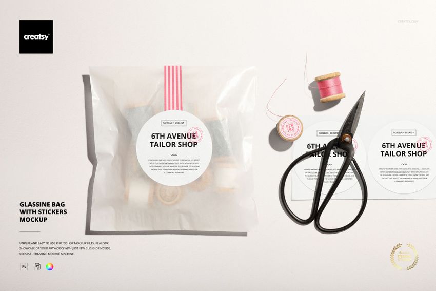 Mockup scene featuring a glassine packaging bag with a sticker label, scissors, pink thread, and two sticker designs.