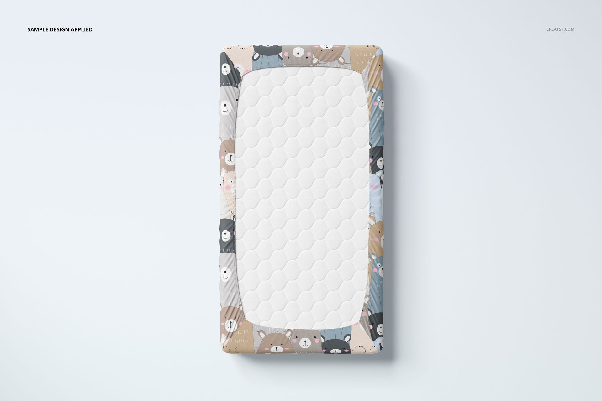 Top view of a crib sheet mockup featuring a white quilted center and colorful animal pattern border on a light background.