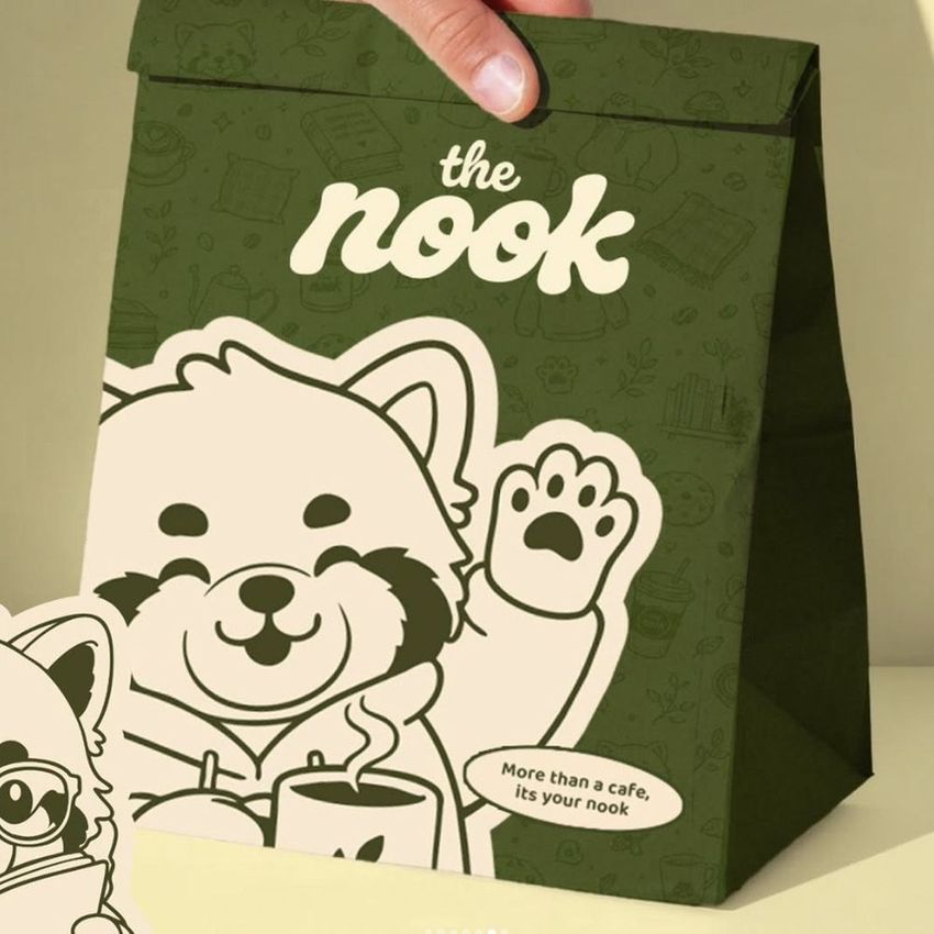 Take-out paper bag mockup featuring a cartoon raccoon illustration, green background, and bold white text on the front.