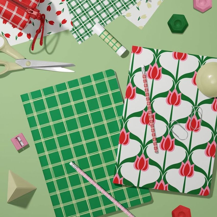 Stationery mockup featuring two A4 notebooks on a green surface, one with a green plaid cover and one with a red tulip pattern.