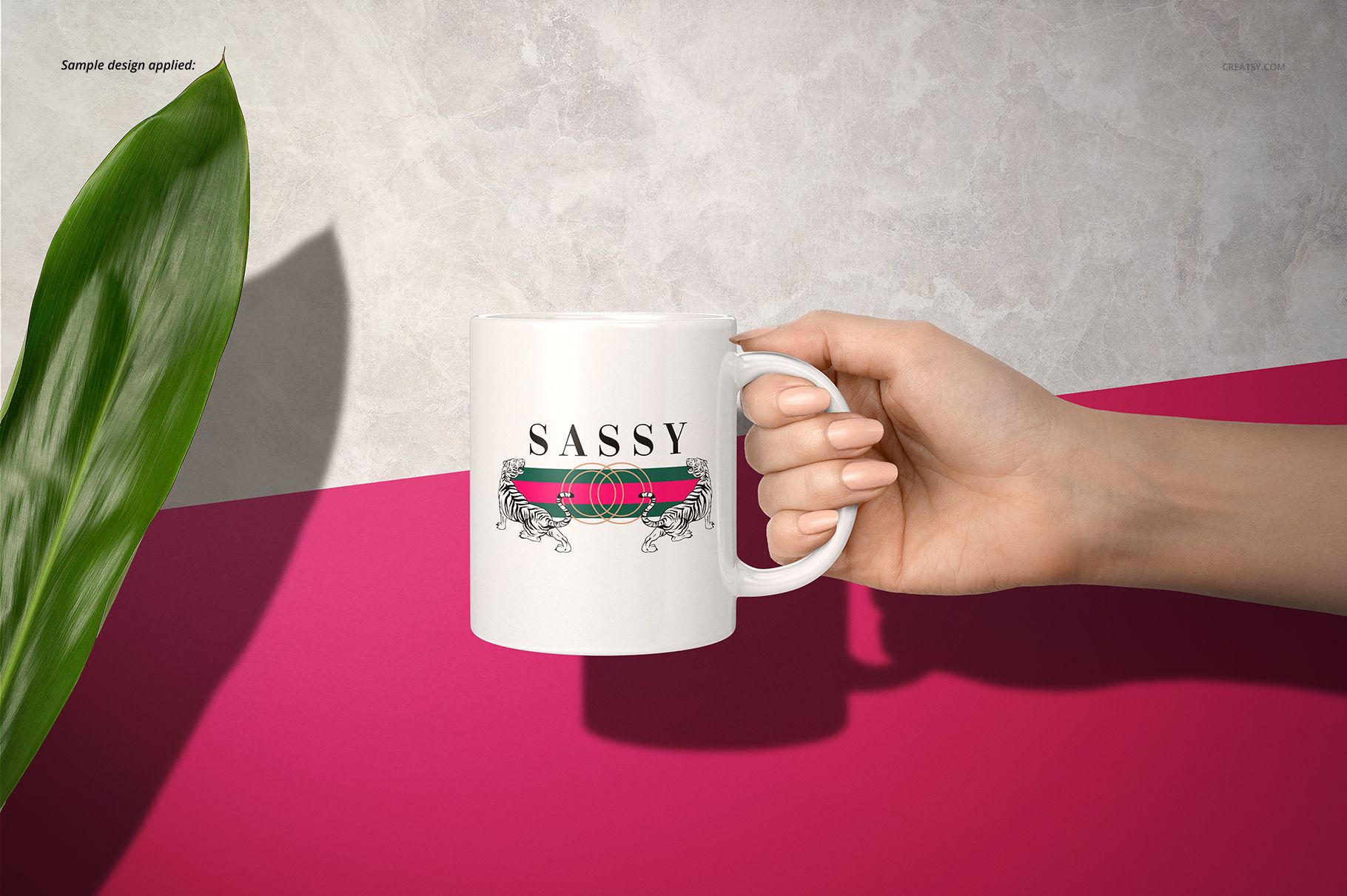 Hand holding a white 11oz mug with a sassy text design, set against a pink and gray background with a green leaf.
