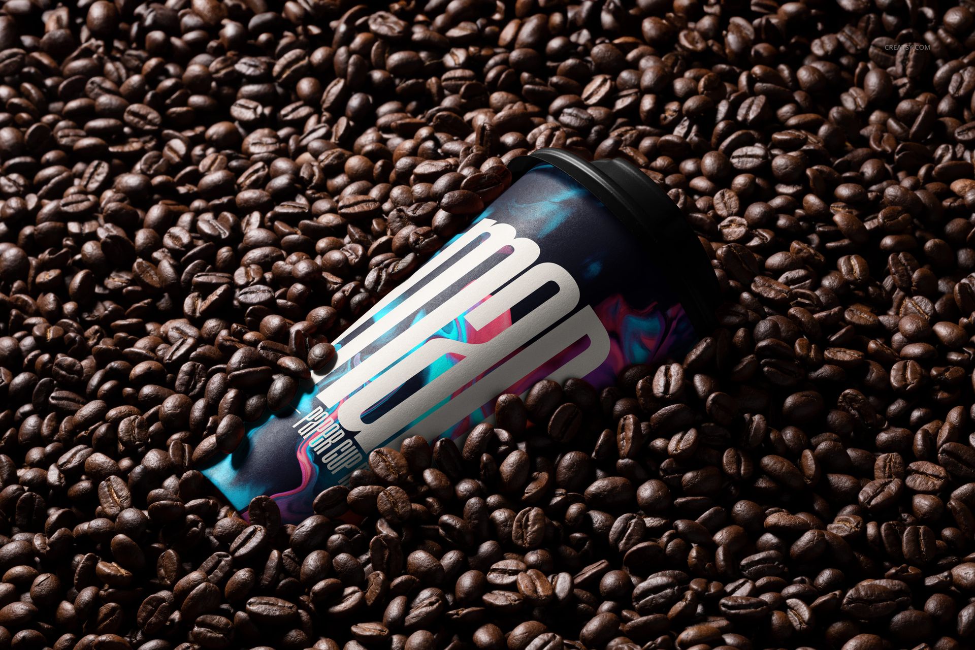 PSD mockup of a paper cup with vibrant patterns, partially buried in a pile of dark roasted coffee beans.