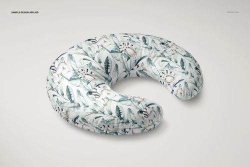 Nursing pillow mockup featuring a crescent shape and leafy animal pattern, displayed on a neutral surface.