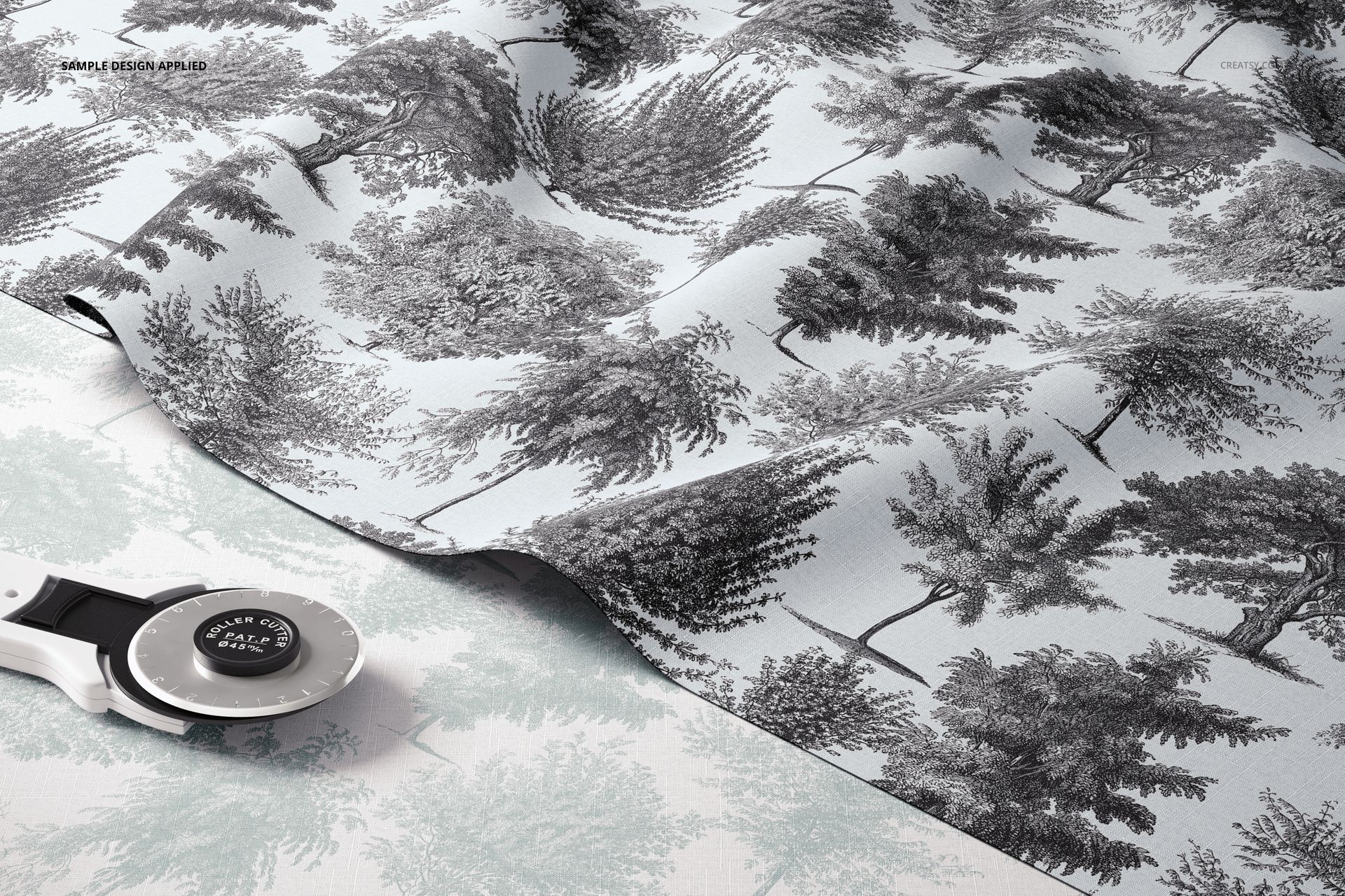 Layered fabric mockup featuring a black and white tree pattern on light blue textile, shown from a top angle.