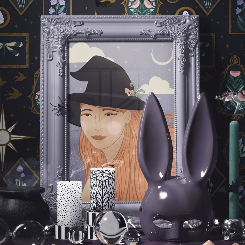 Halloween picture frame mockup featuring an art print of a witch, set against a dark patterned wall with themed props.