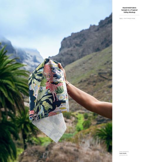 Fabric sample featuring colorful botanical designs held up against a scenic mountain landscape, PSD mockup style.