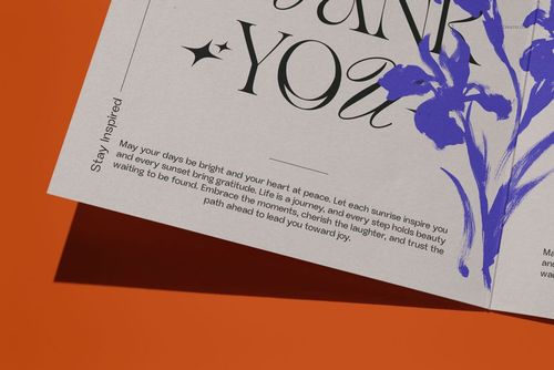 Close-up view of a square greeting card mockup featuring elegant typography and blue flower artwork on orange background.