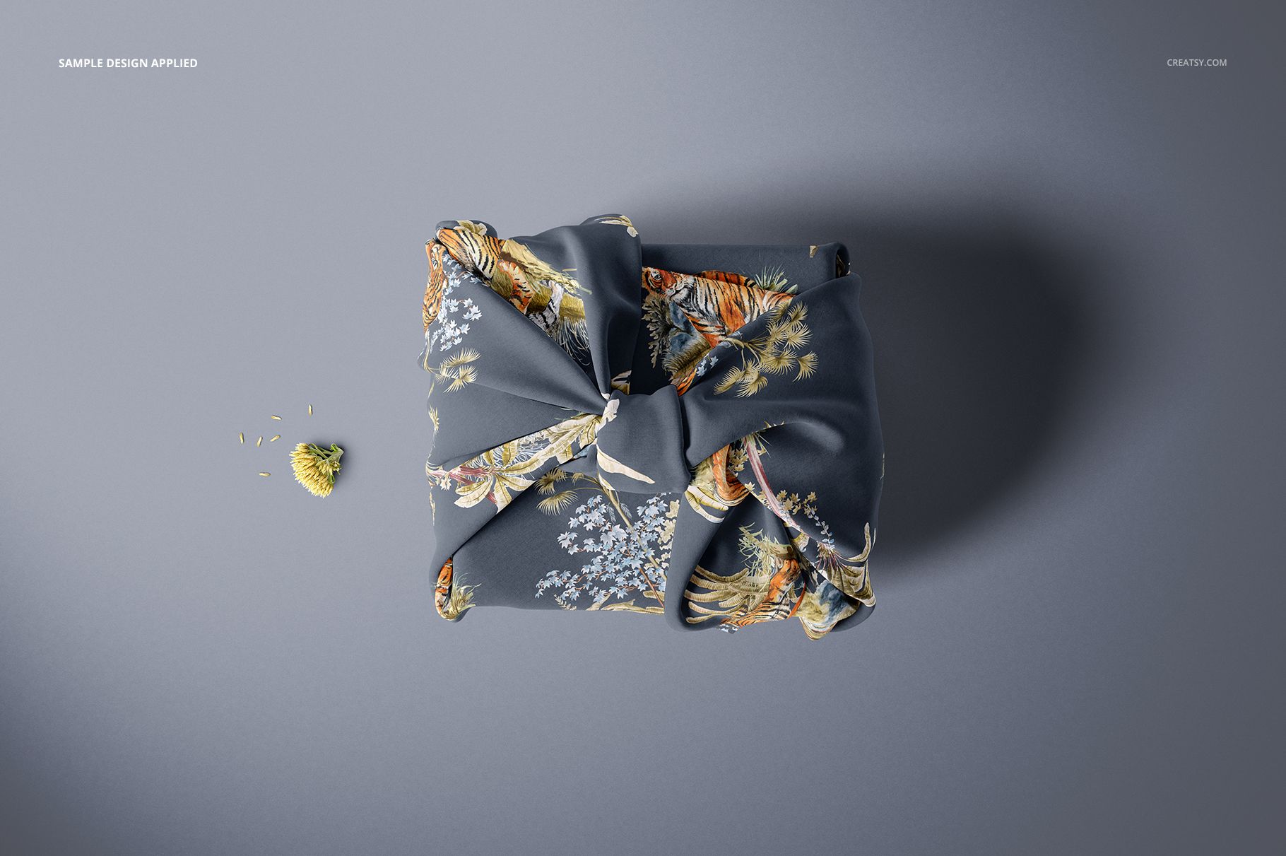 Top view of a fabric gift wrap mockup featuring a dark cloth with intricate floral and animal print, styled in a knot.