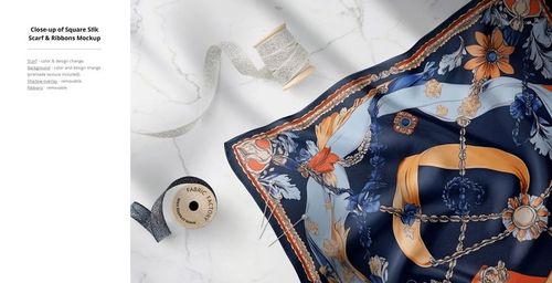 Silk fabric mockup featuring detailed floral and chain motifs in navy, orange, and beige, shown from above on marble.