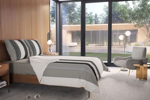 Stylish bedding mockup in a sunlit room with wood panel walls, gray armchair, and minimalist decor elements.