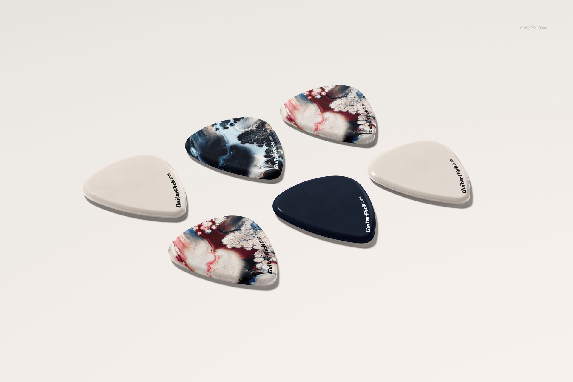 PSD mockup of guitar picks with a mix of solid white, navy, and marbled patterns, viewed from above on a pale background.