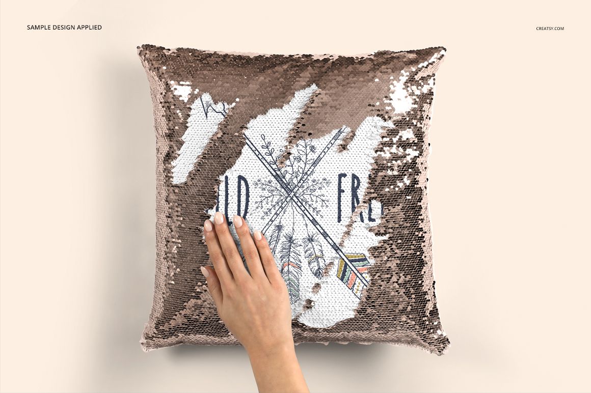Hand brushing sequins on a square pillow mockup, exposing customizable printed design, neutral background.