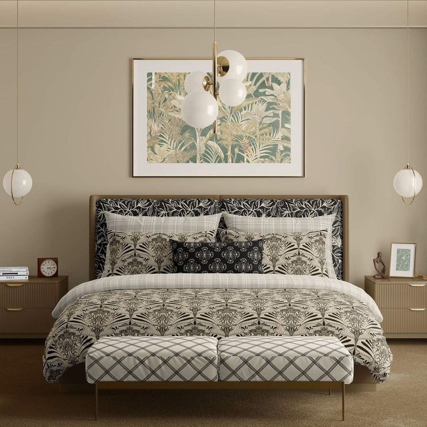 Bedroom scene bedding mockup showing a bed with patterned duvet and pillows in neutral tones, framed art above, and modern pendant lights.