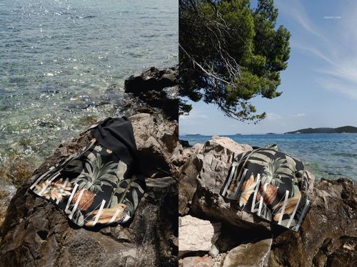 Mockup of a patterned waffle beach towel draped over rocks by the sea, with pine trees and islands in the background.