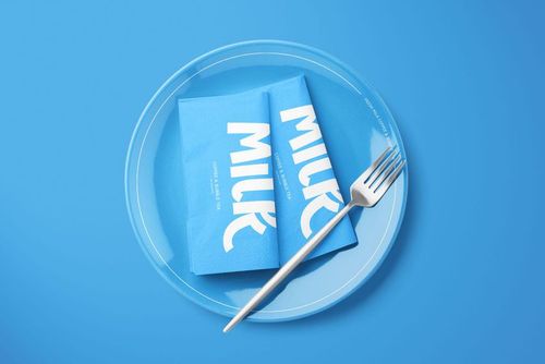 PSD mockup featuring folded blue napkins with white print on a glass plate, fork positioned to the side, blue backdrop.