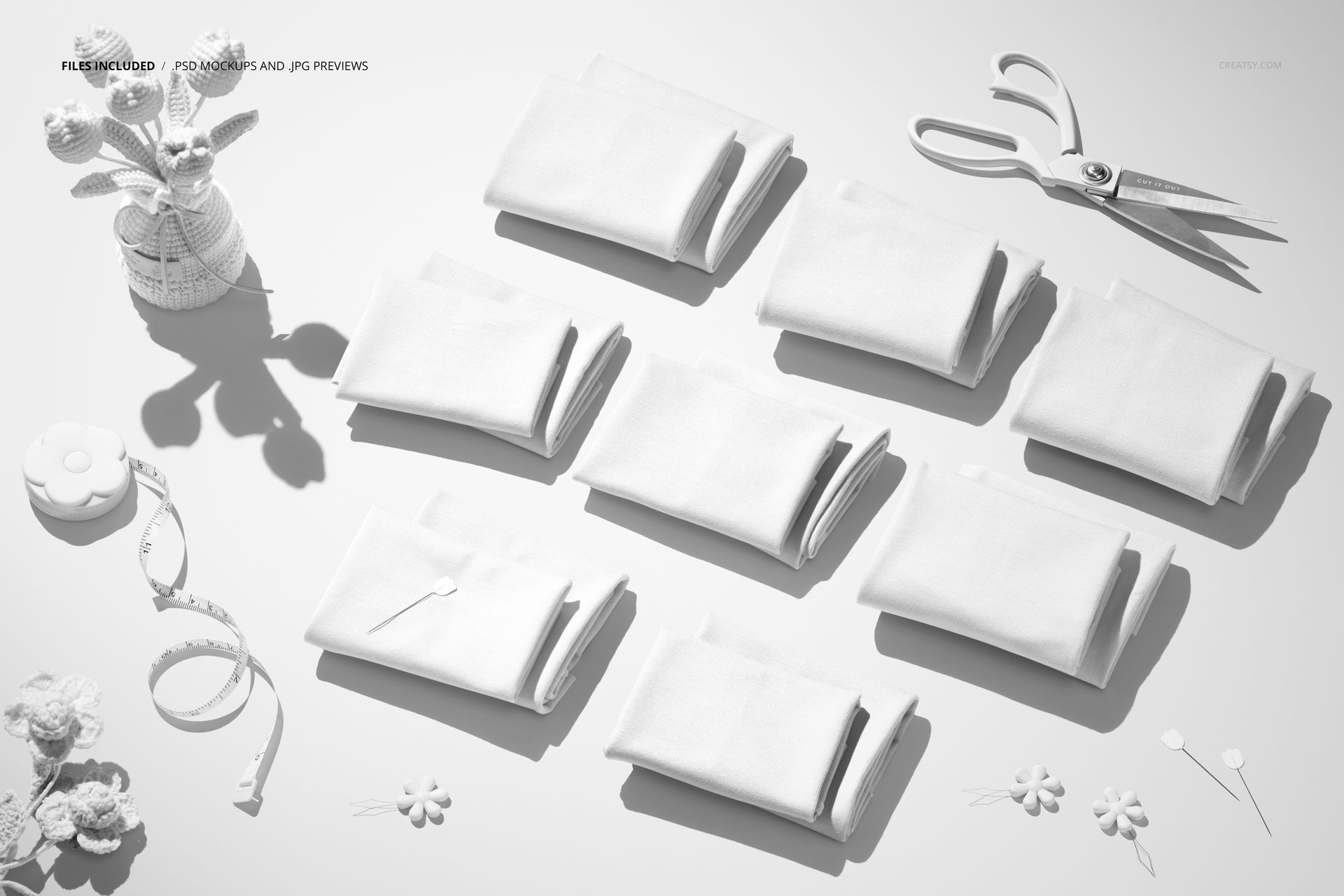 PSD mockup showing nine folded jersey fabric pieces on a flat surface with knitted flowers and sewing tools nearby.