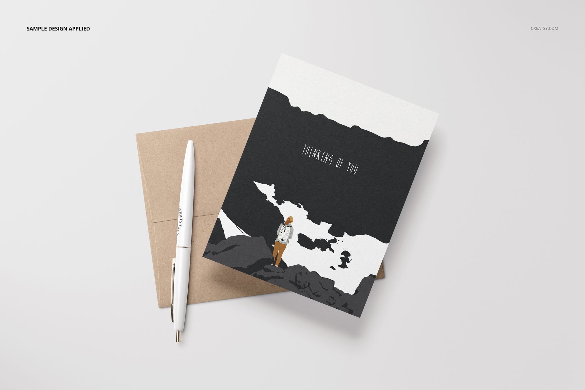 Front view of an A2 card mockup featuring a minimal illustration, accompanied by a brown envelope and a white pen.