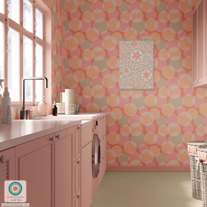 Laundry room mockup with pastel pink cabinets, patterned wallpaper in peach and pink tones, and a front-loading washer.