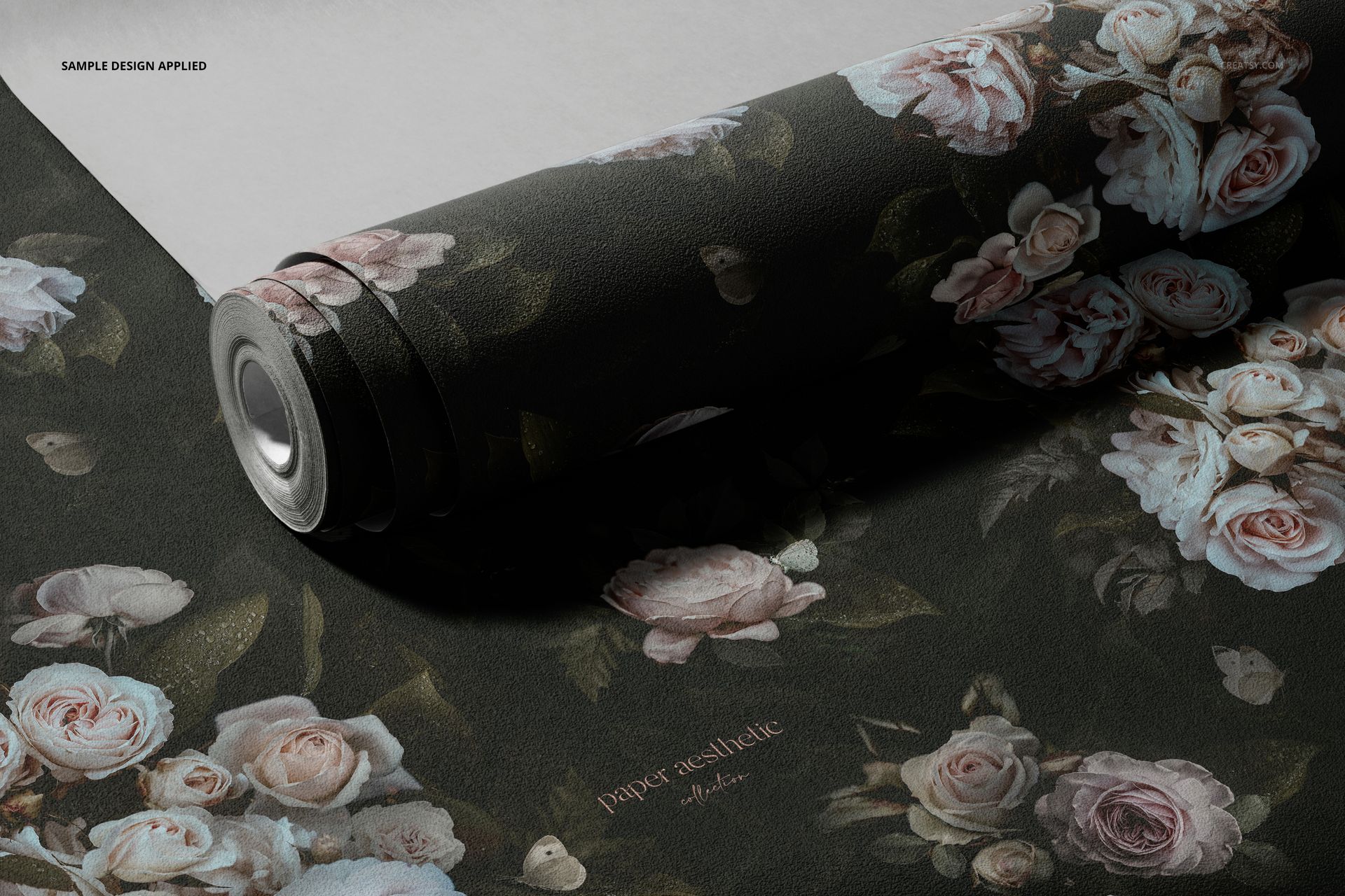Dark floral non-woven vinyl wallpaper mockup featuring pink and white roses, displayed partially unrolled on a flat surface.